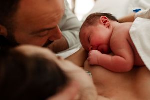 Black and white image showing tender interaction with a newborn.