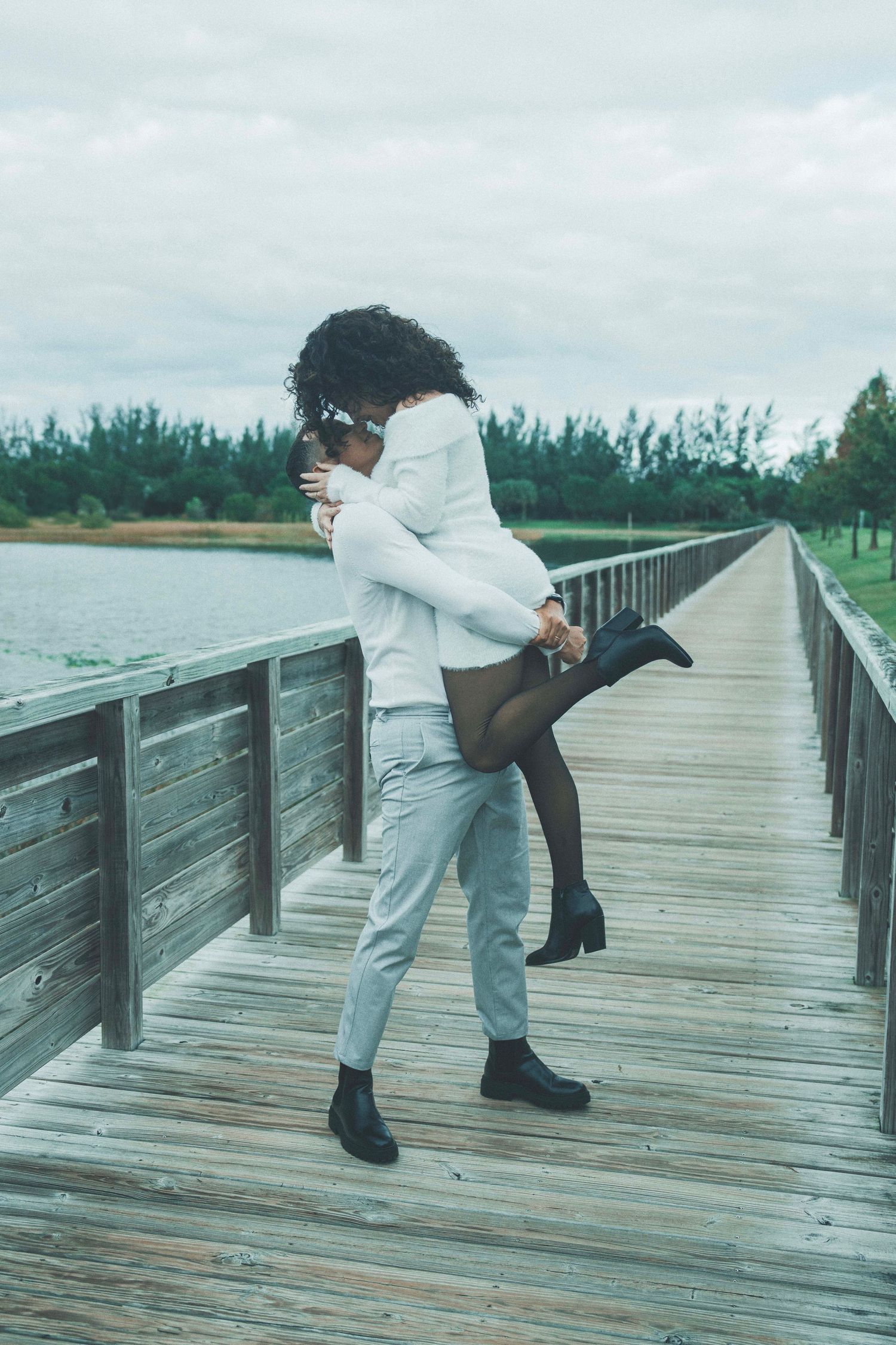 Romantic couple share intimate moments in a dreamy outdoor setting with soft mint green foliage surroundings.