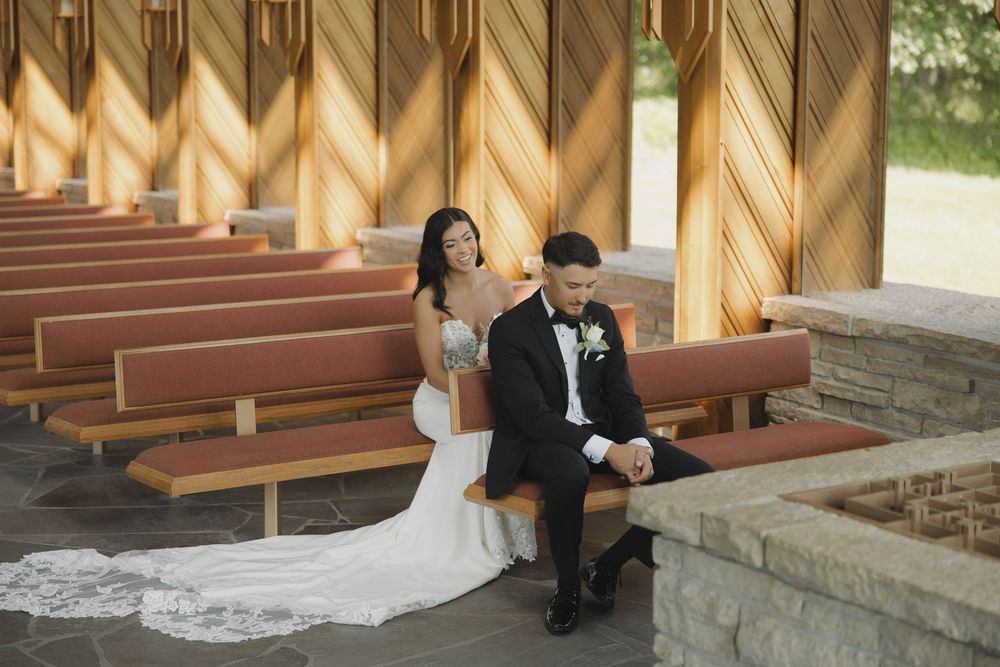 Beautiful rustic church pews in natural wood tones line an outdoor wedding ceremony space.