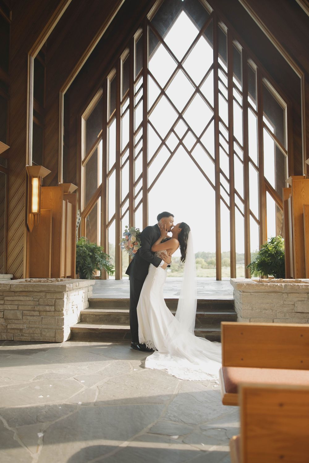 Wedding venue interior with dramatic wooden beams and natural light streaming through geometric windows.