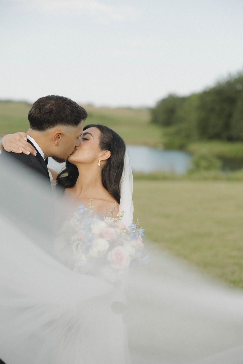 Wedding veil floating gracefully in the breeze on a sunny afternoon in a natural outdoor setting.