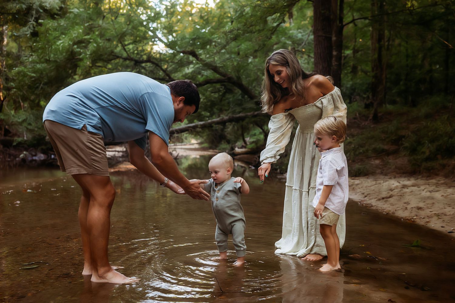 A group explores a shallow creek together during a warm summer afternoon in a forest setting.