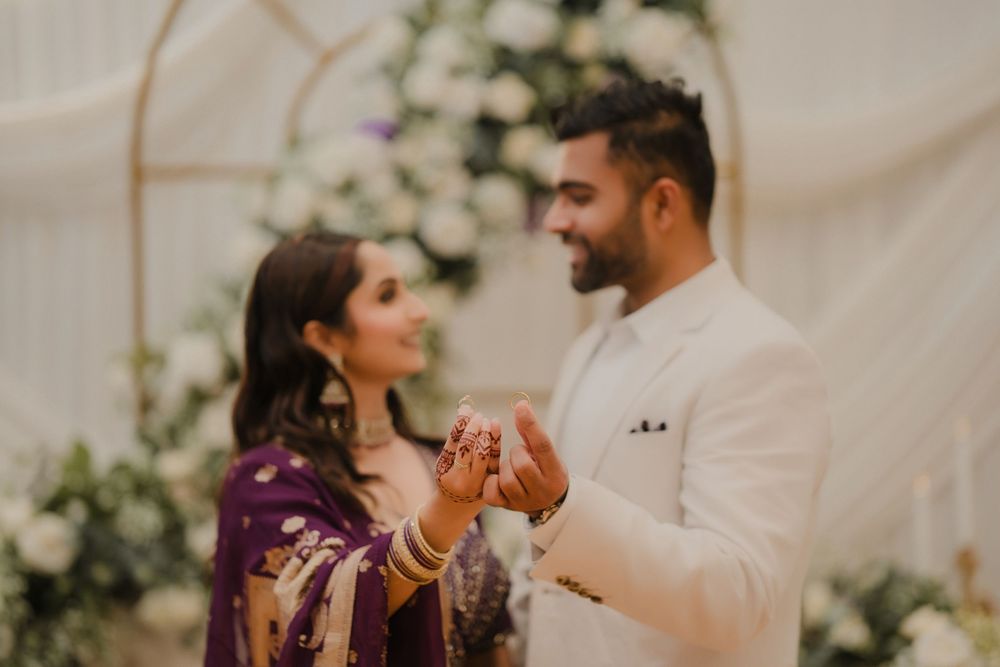 A couple sharing a tender moment at an elegant wedding ceremony surrounded by white floral decorations.