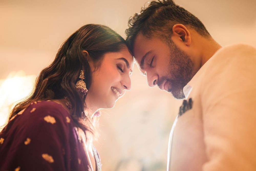 Young couple in traditional Indian attire share an intimate moment in warm lighting.