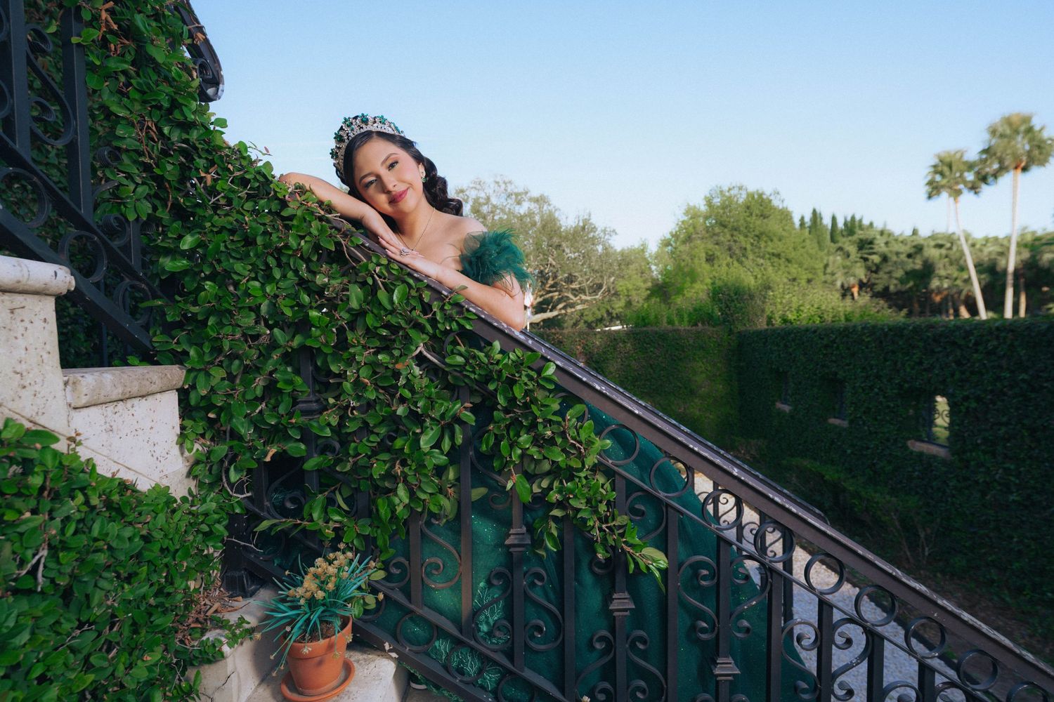 Dramatic emerald dress photographed on outdoor staircase surrounded by lush greenery.