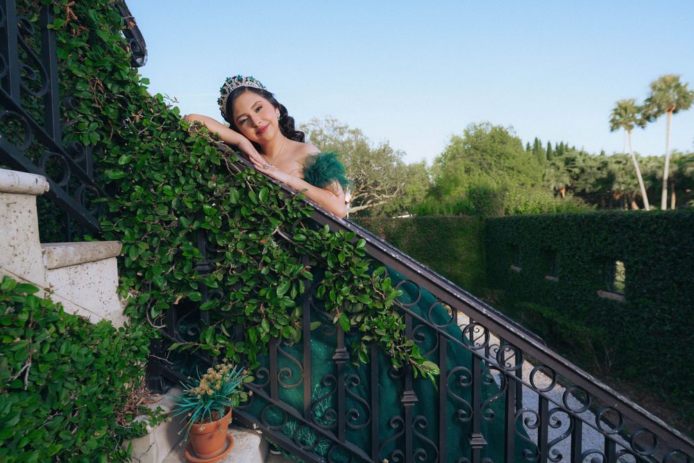 Dramatic emerald dress photographed on outdoor staircase surrounded by lush greenery.