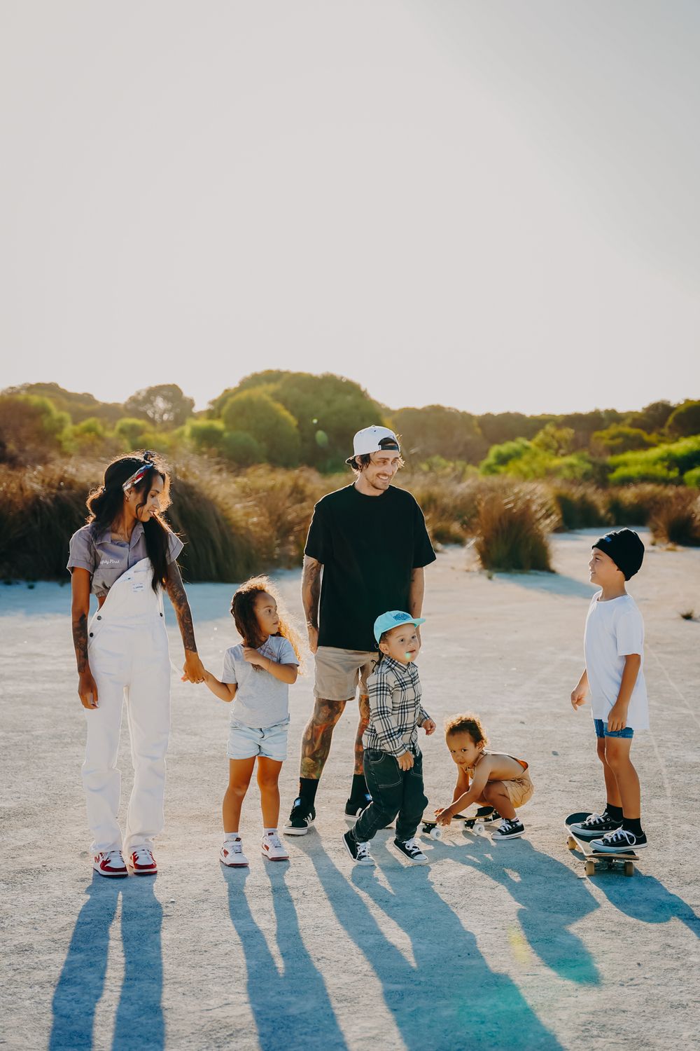 Family enjoying a casual day together outdoors casting long shadows on a blue-tinted ground at sunset.