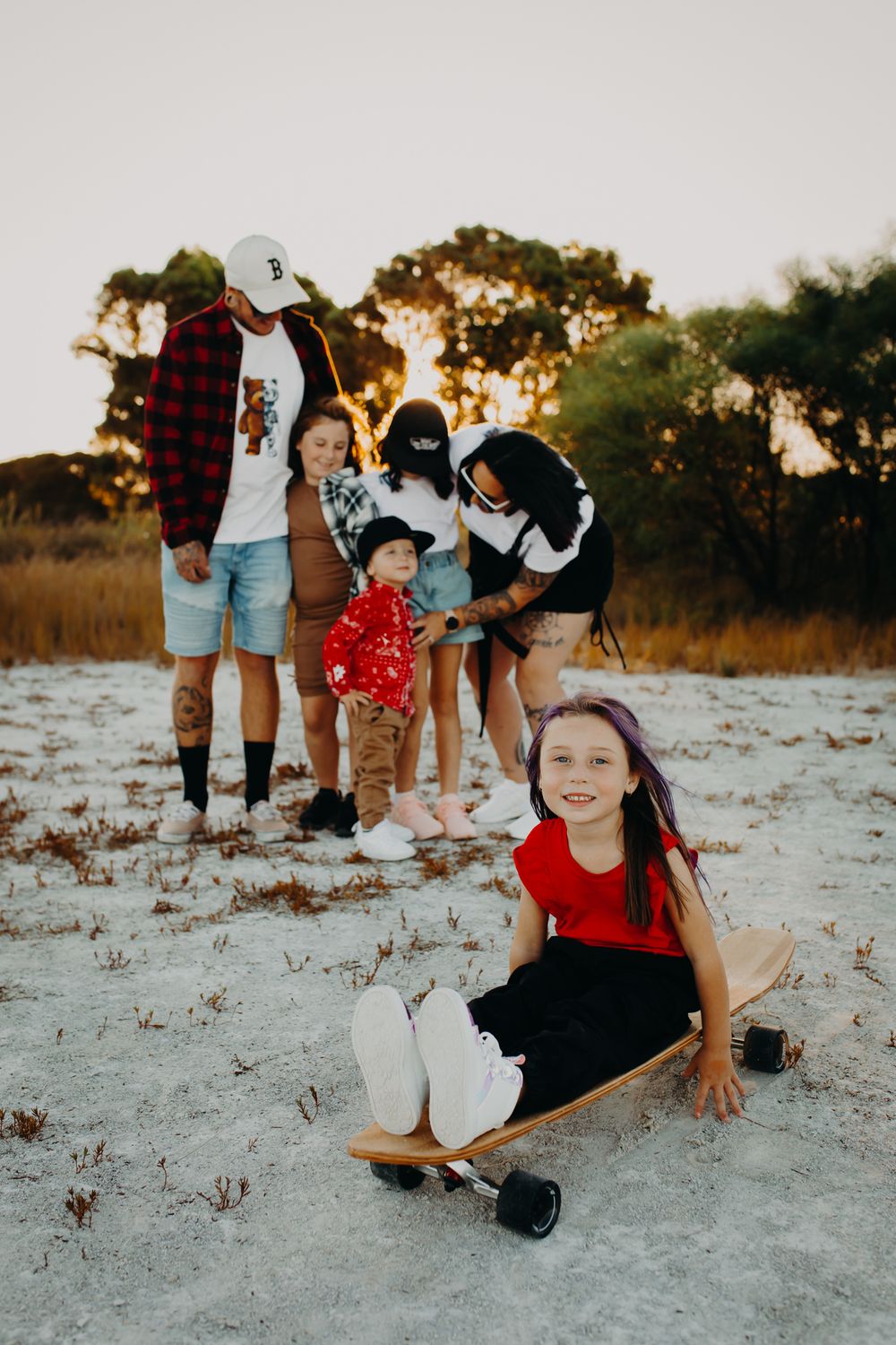 A heartwarming family session at sunset unfolds on a white sandy beach with playful poses and warm lighting.