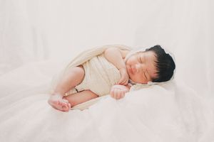 Peaceful newborn baby sleeping soundly on soft white bedding.