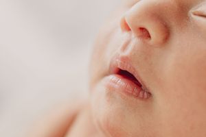 Artistic macro photograph of a sleeping infant's lips and nose against white background.