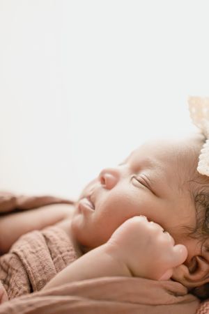 Peaceful sleeping baby in soft brown clothing against light background.