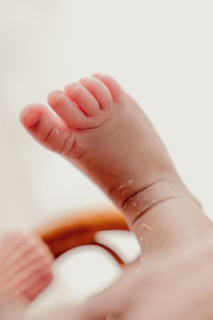 Close up of tiny baby foot with delicate toes against white background.