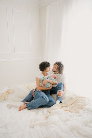 Two people share an intimate moment while lounging on white bedding.
