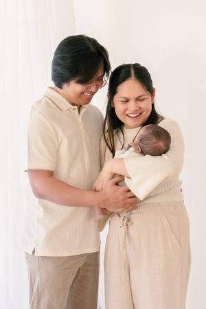 Happy family sharing intimate moment with newborn baby in neutral-toned setting.