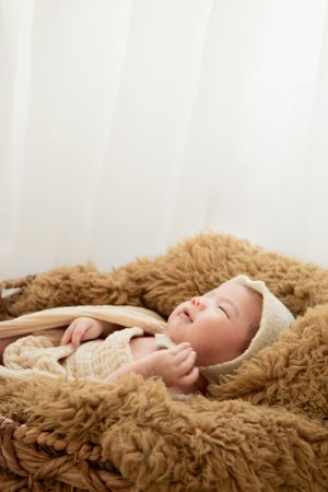 Peaceful newborn portrait on brown fluffy blanket with white backdrop.