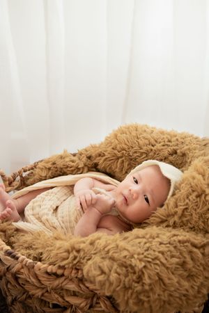 Newborn resting peacefully on fluffy brown blanket during professional photo session.