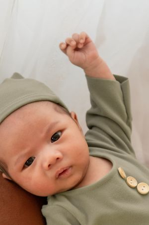 Close-up of baby wearing sage green outfit with decorative buttons.