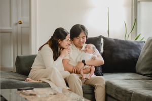 Family gathering on grey couch during intimate home photo session.