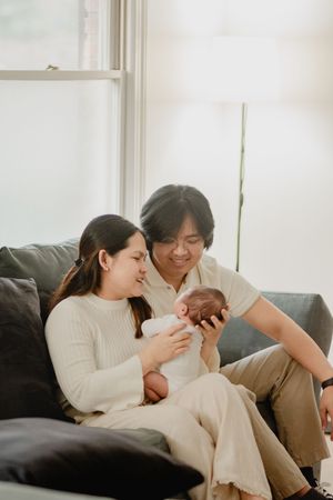 Loving family interaction with their newborn baby while relaxing on a comfortable couch.