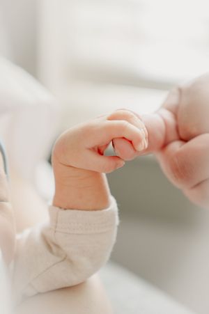 Close-up of baby's tiny hand reaching out in soft natural lighting.