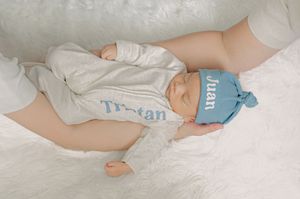 A baby's feet peek out from under a personalized blue blanket.
