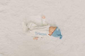A close-up view of a baby's blanket with blue embroidered text.