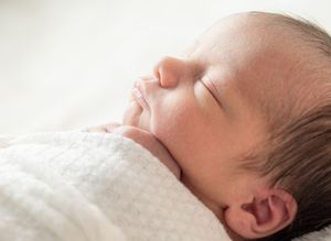 A sleeping newborn's profile against a soft white background.