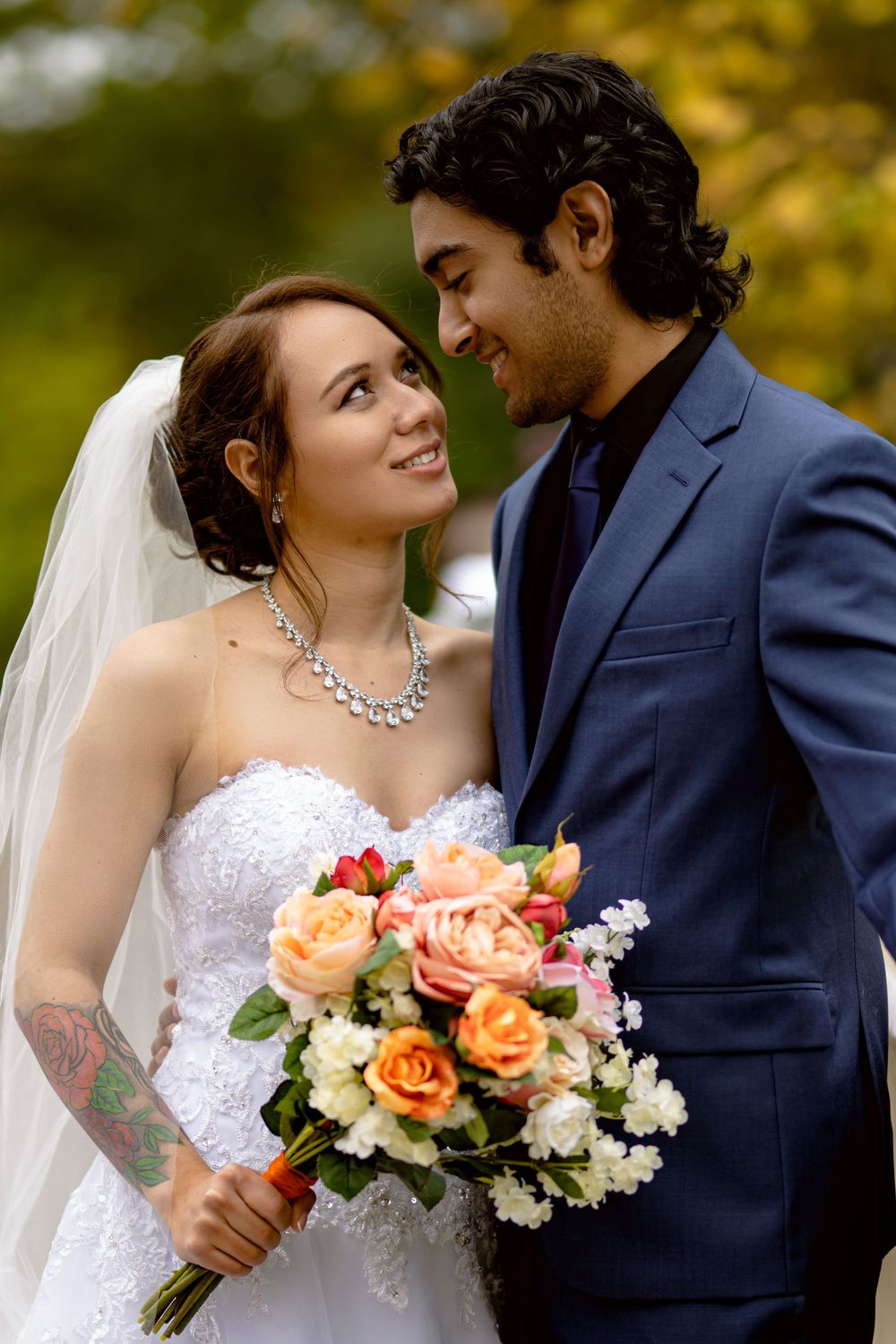 A joyful wedding portrait with autumn colors, featuring a stunning white dress and navy suit.