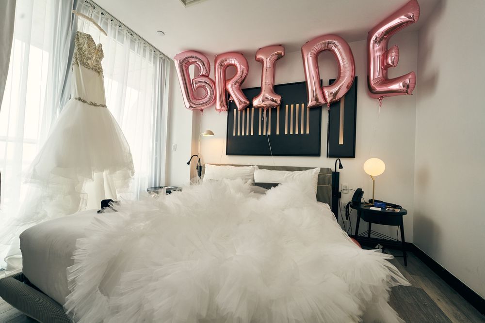 White wedding dress and pink 'BRIDE' balloons displayed in modern hotel room. at the WIlliam Vale Hotel