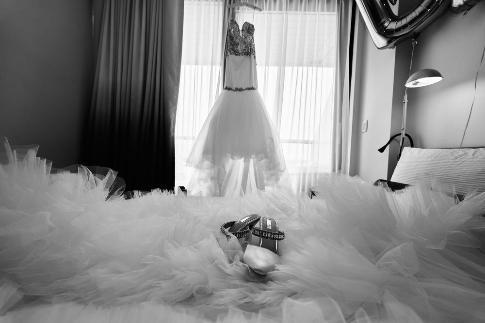 A white wedding dress hangs dramatically over layers of tulle against dark curtains. at the WIlliam Vale Hotel