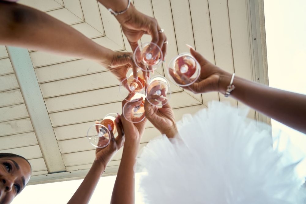 Close-up shot of hands toasting with champagne glasses amid white tulle fabric. at the WIlliam Vale Hotel