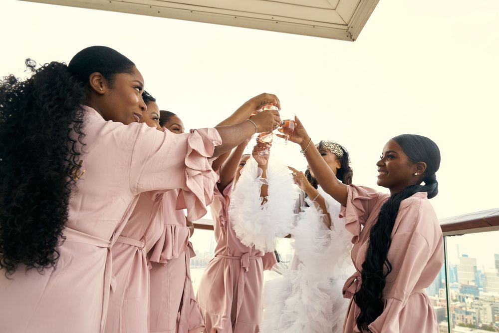 Bridesmaids in pink robes share drinks and laughter during pre-wedding celebrations. at the WIlliam Vale Hotel