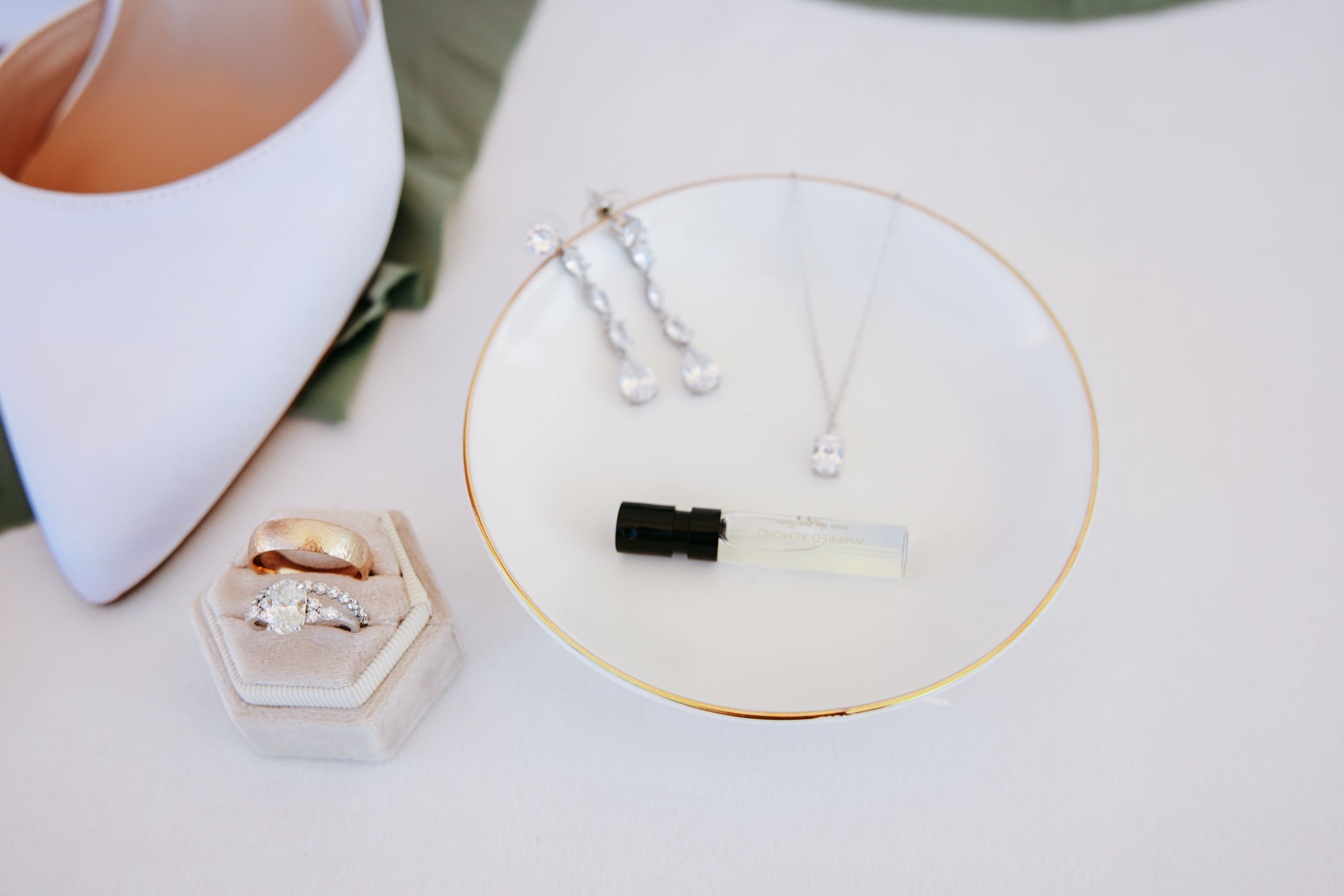 Wedding accessories including jewelry and rings displayed on a white plate with golden rim.