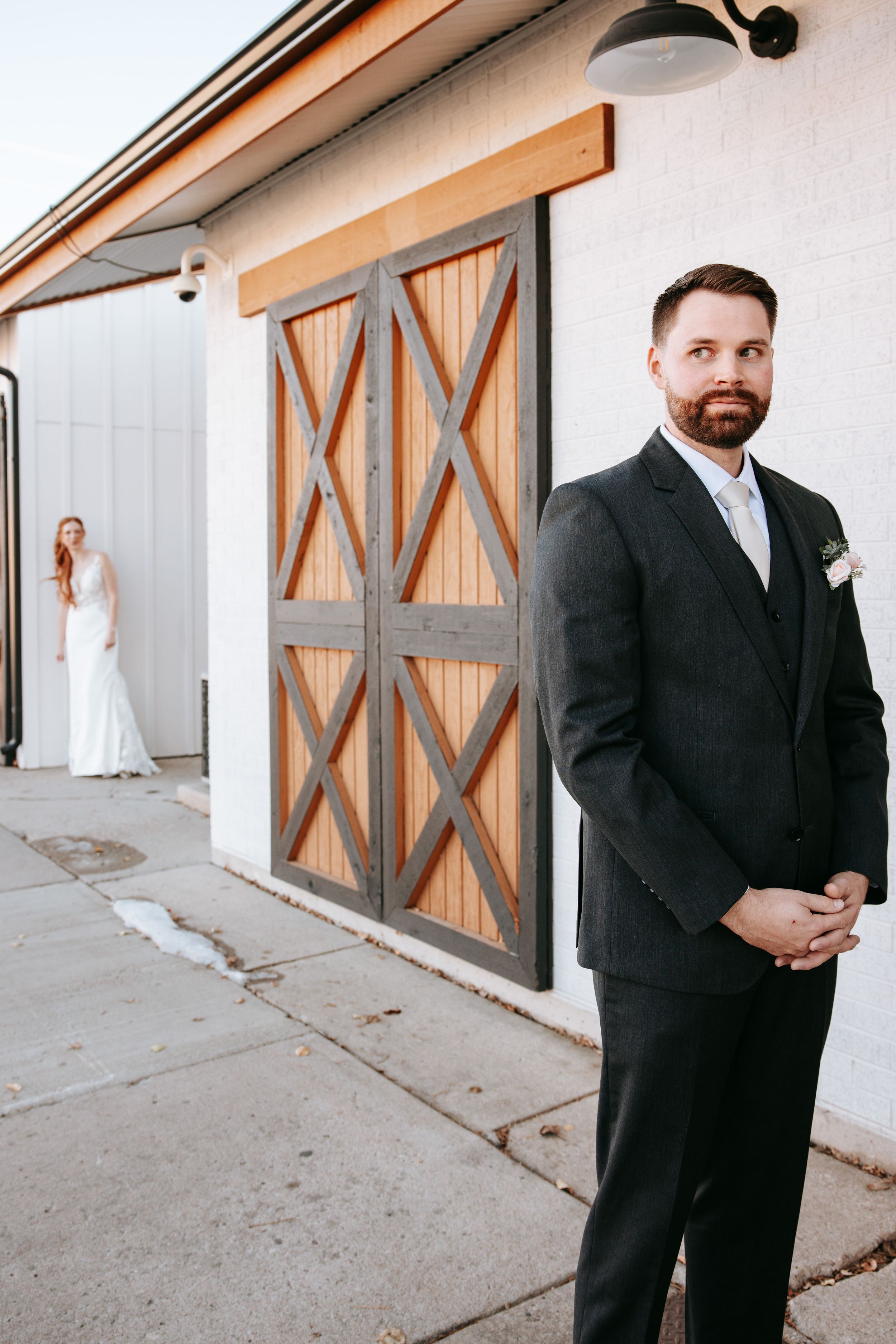 Wedding scene with rustic wooden barn doors and formal attire.