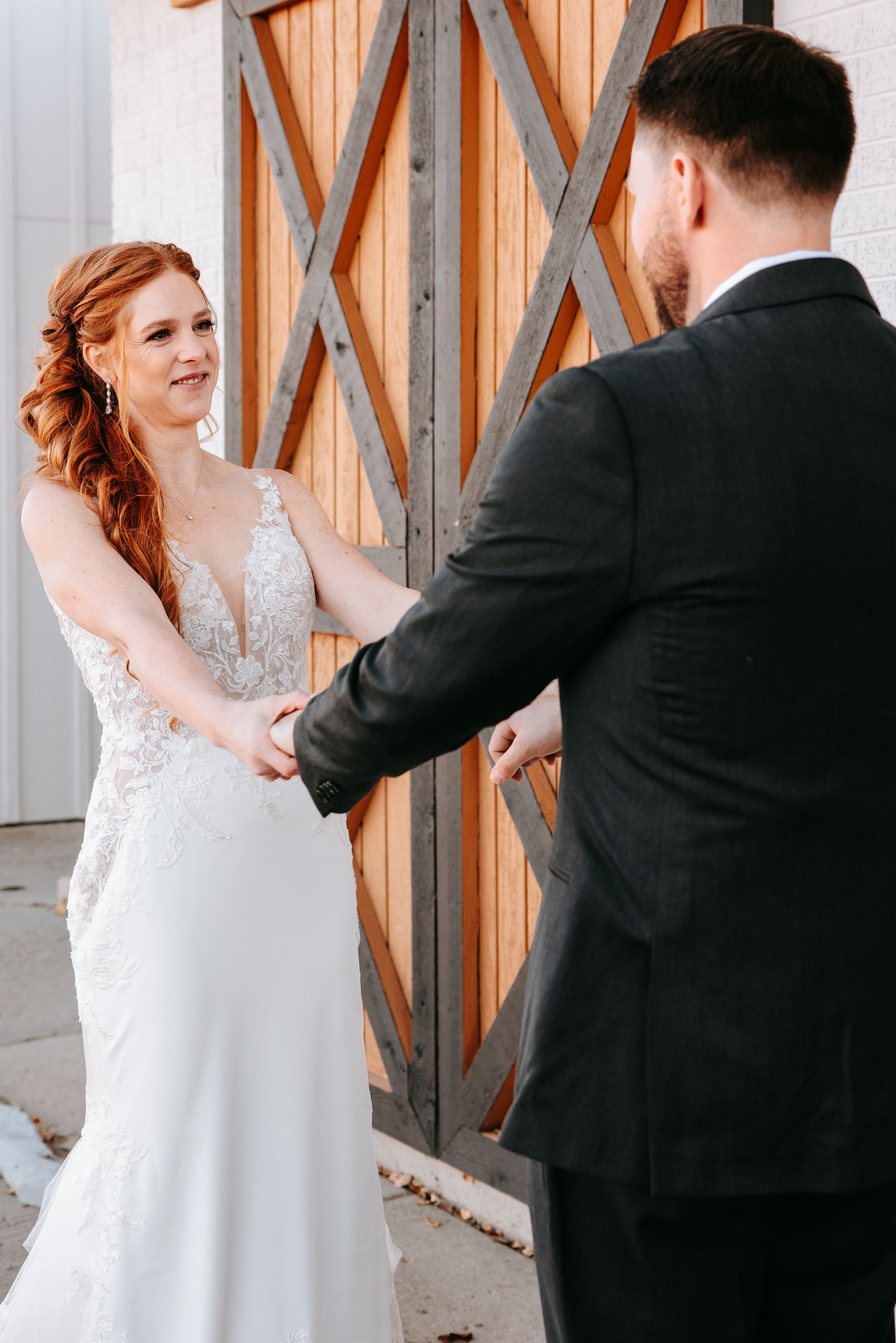 Joyful wedding moment captured in front of wooden barn doors with X pattern design.