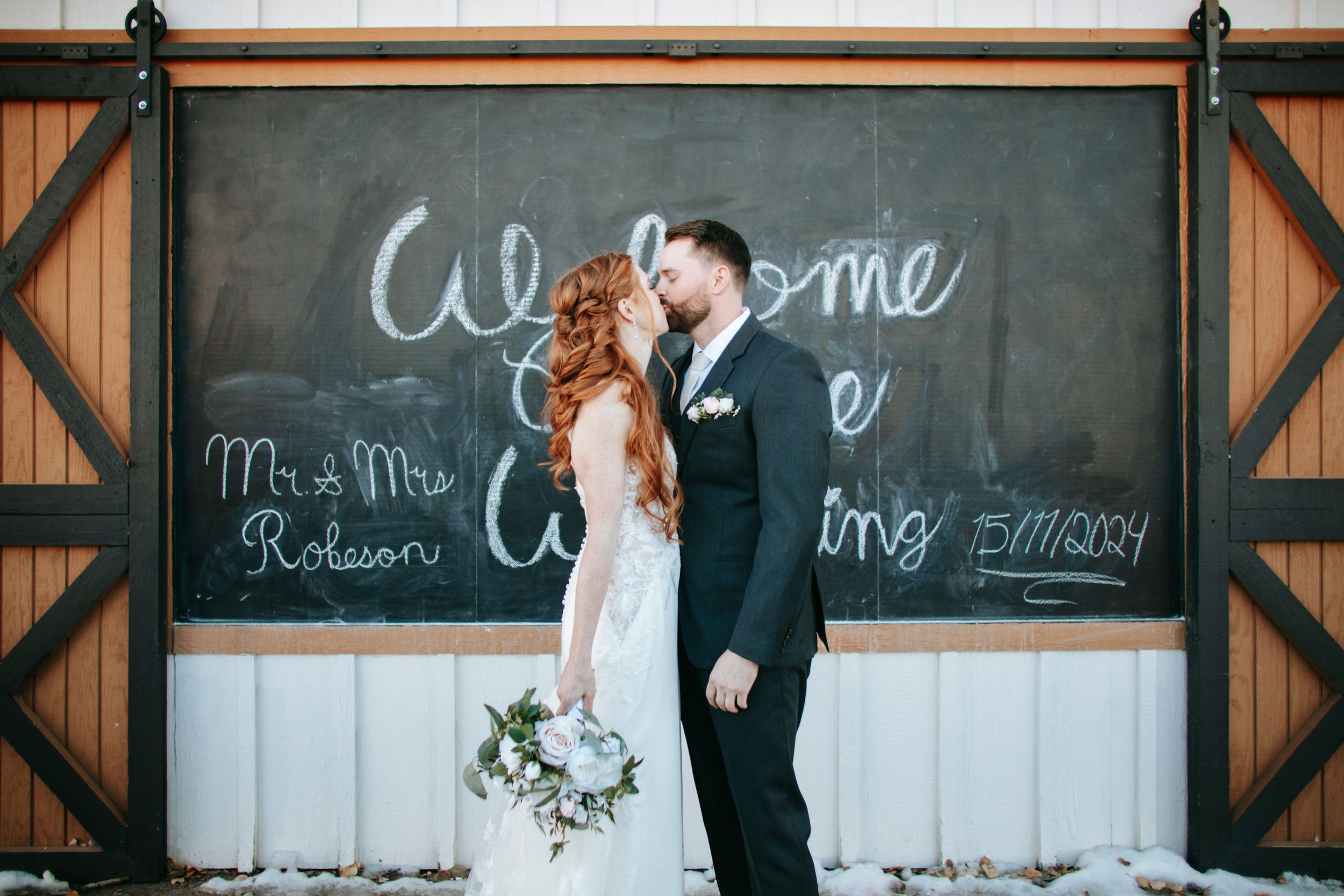 Wedding ceremony setup with rustic chalkboard decor and wooden barn accents.