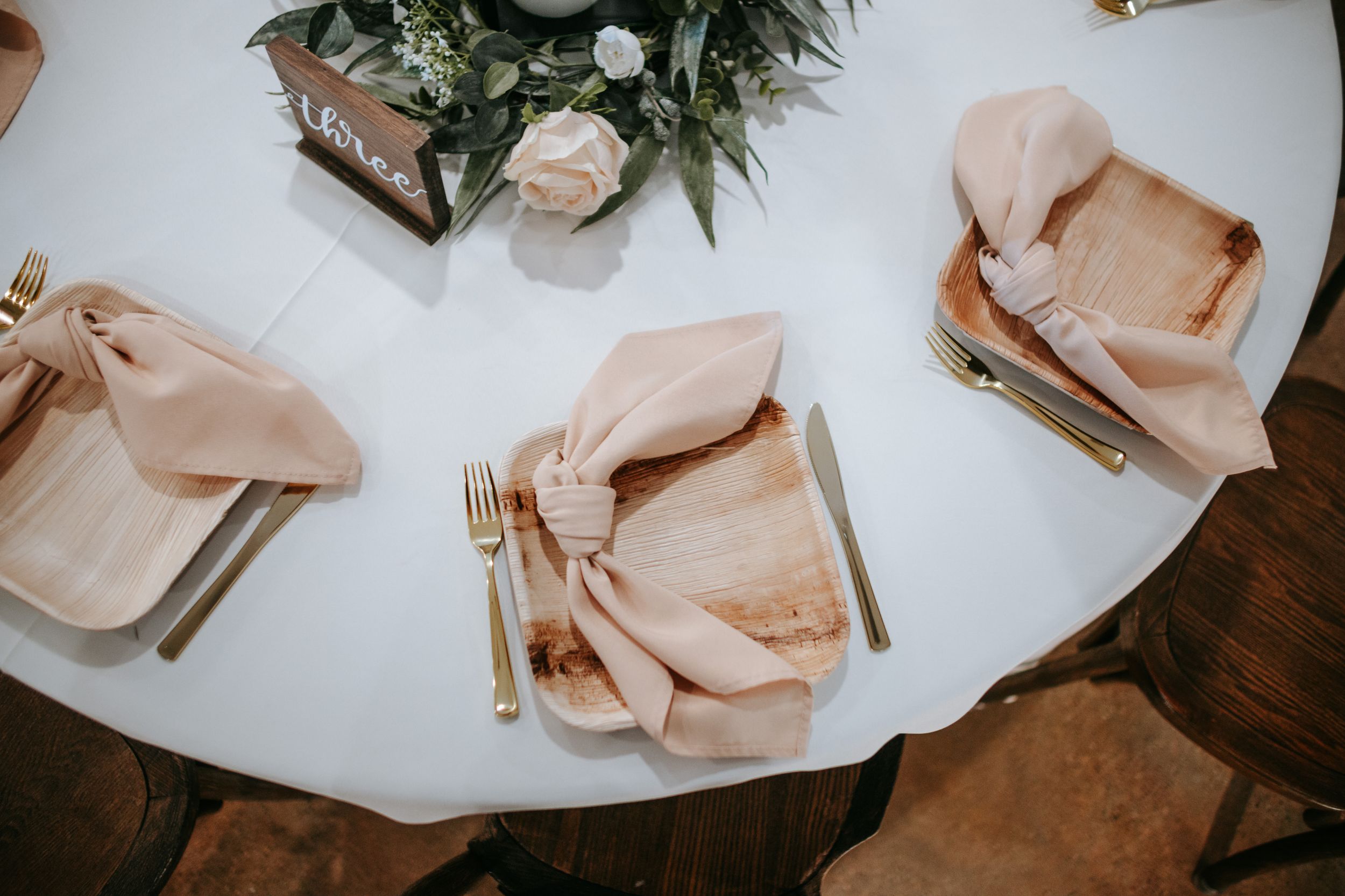 Several torn and crumpled sheets of light pink or peach colored paper lay scattered on a white surface.