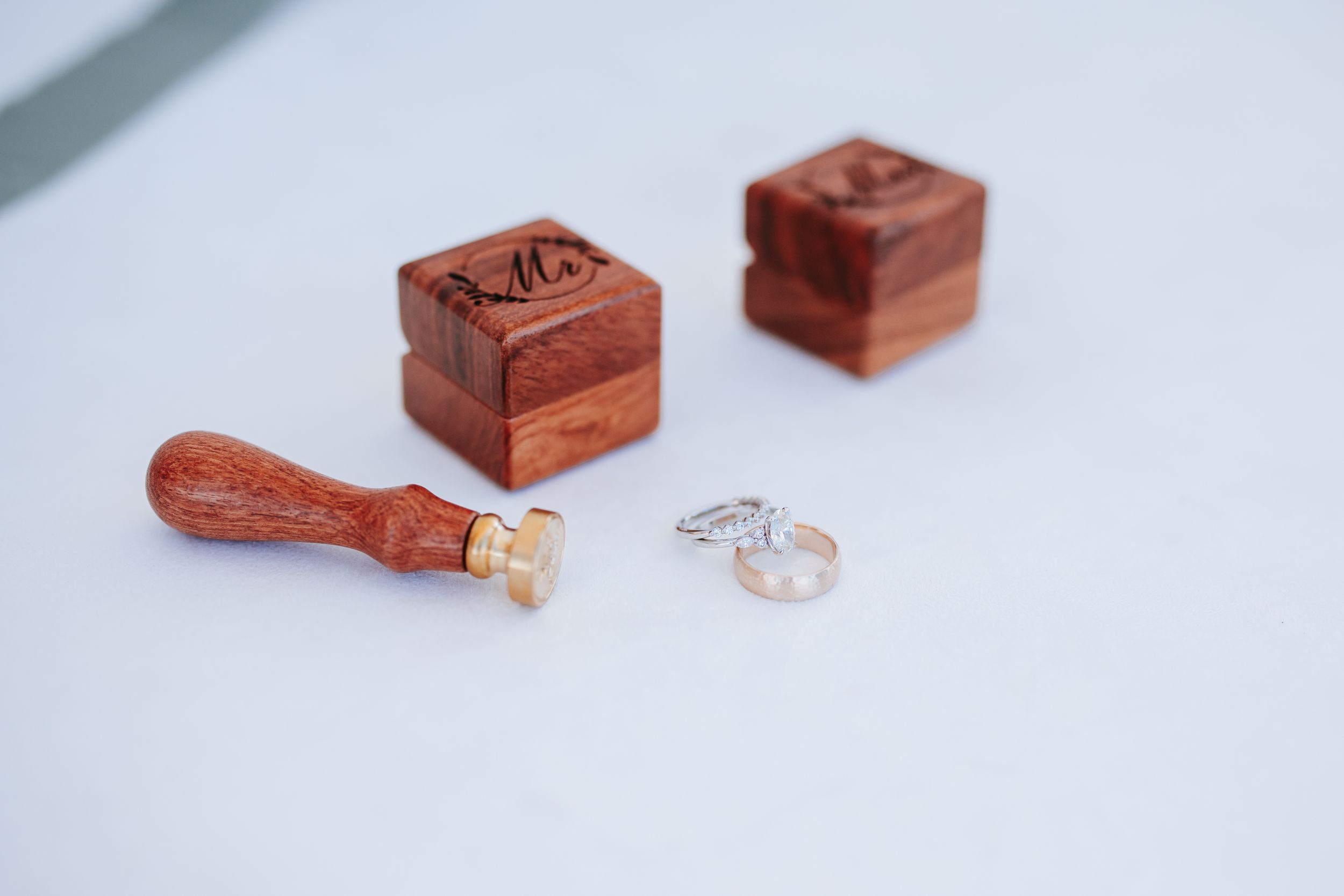 Wooden ring boxes and engagement rings displayed on white surface.