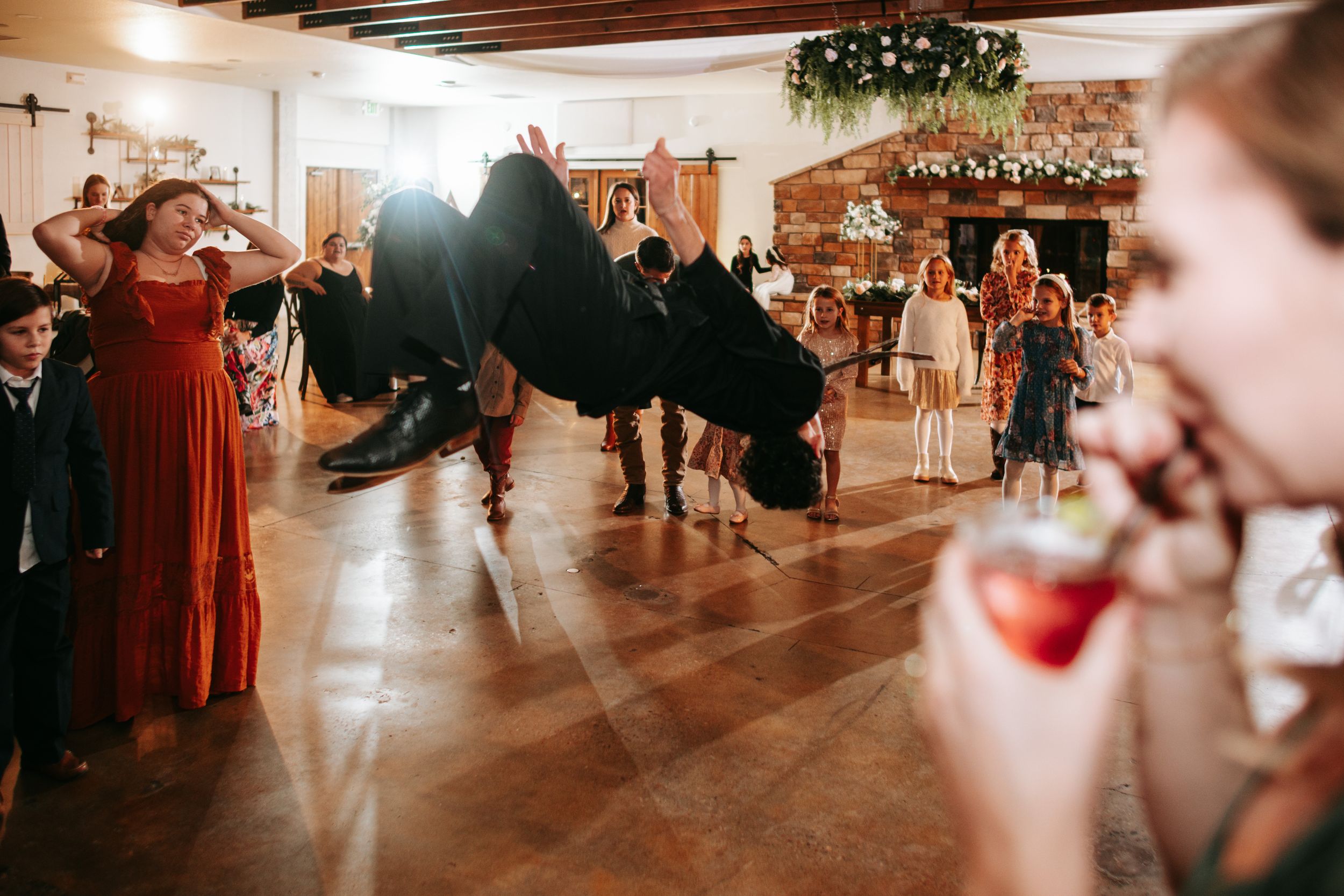 Wedding celebration in a rustic venue with wooden ceiling beams and decorative string lights.