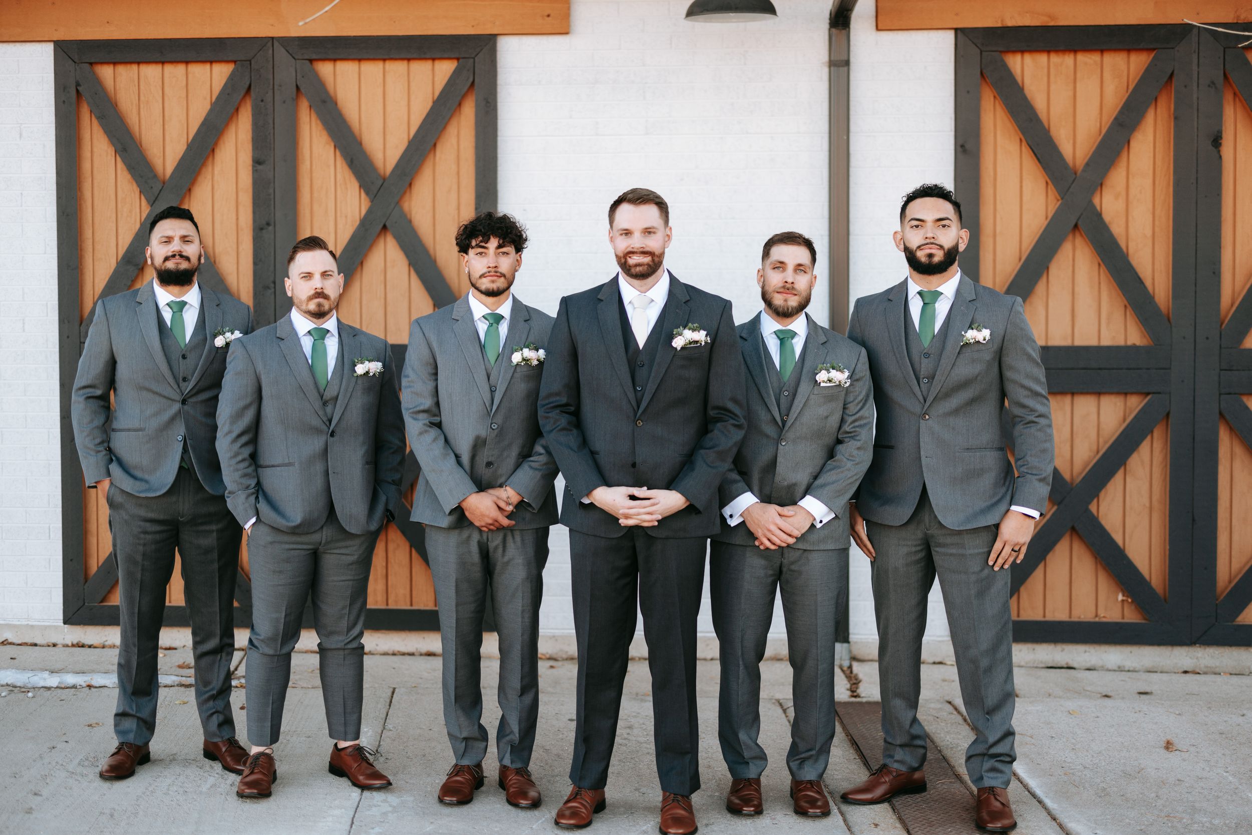 Wedding party poses in formal attire with groomsmen wearing matching gray suits.