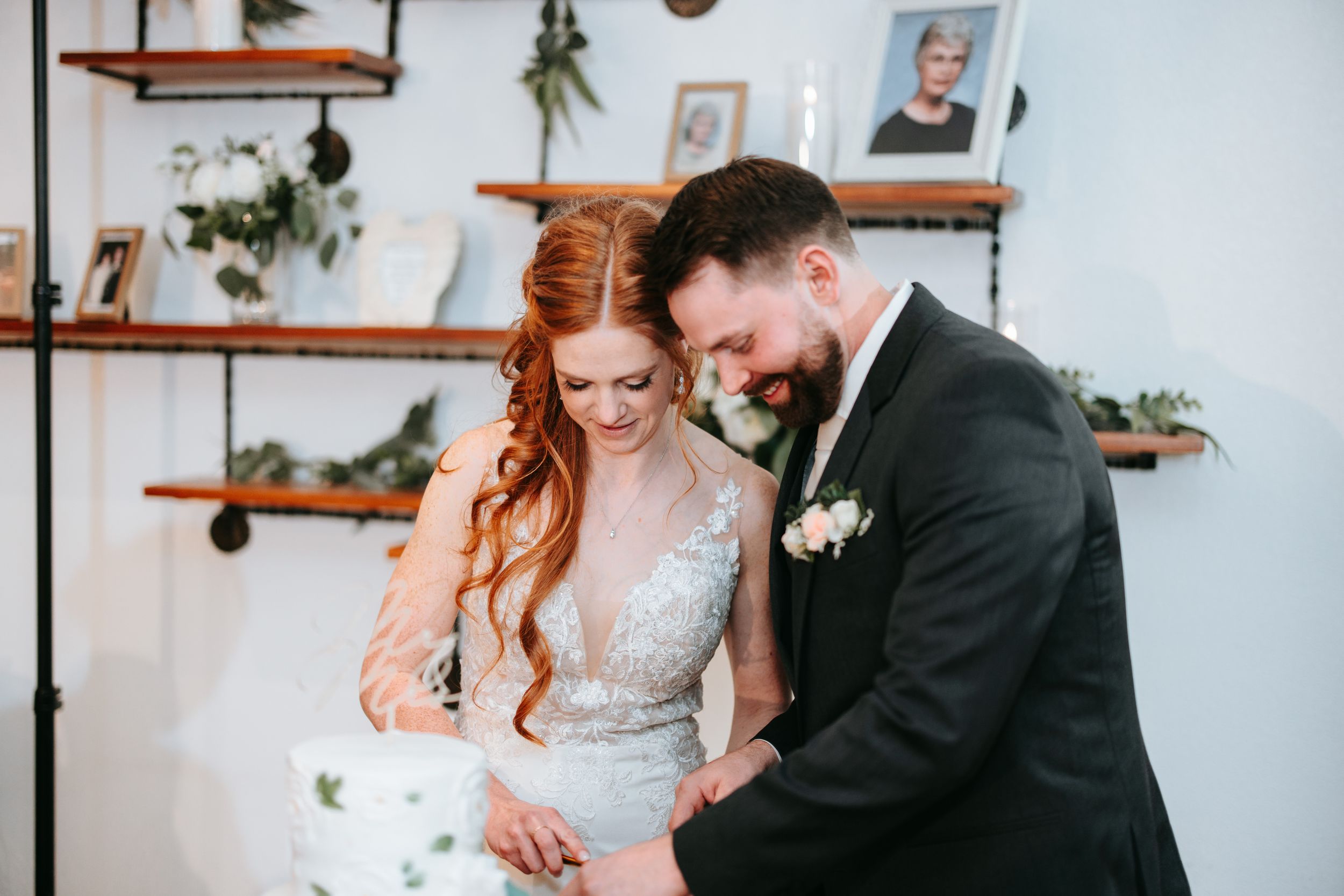 A loving moment captured as a couple shares their first cake cutting experience at their wedding reception.