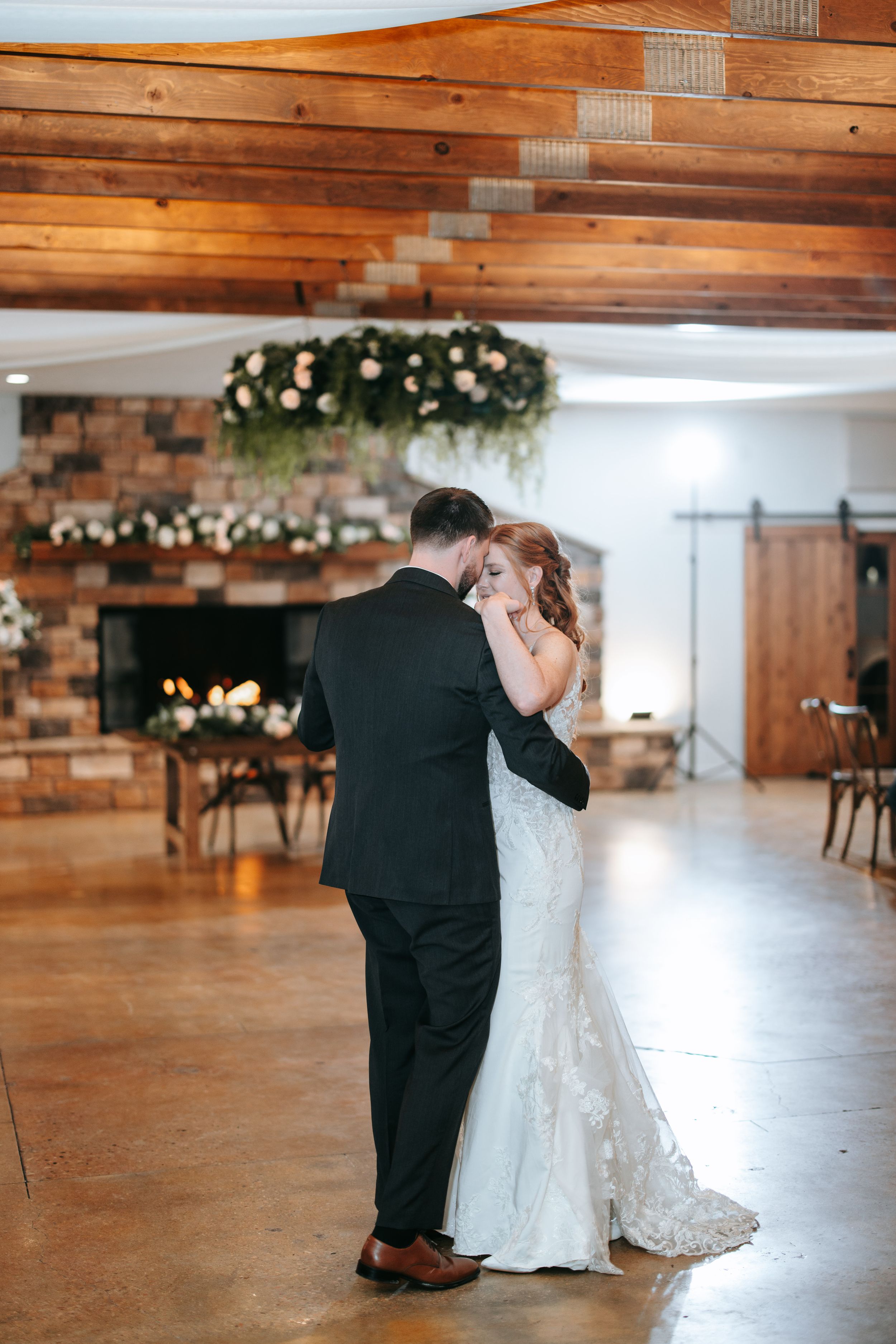 First dance sequence between newlyweds in rustic wedding venue with wooden walls and decorative lights.