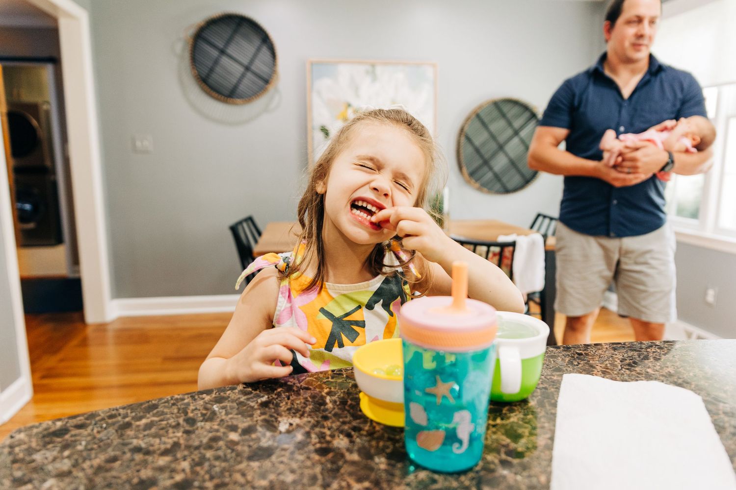 Photo showing a joyful breakfast scene with a child and parent eating breakfast at a kitchen counter.