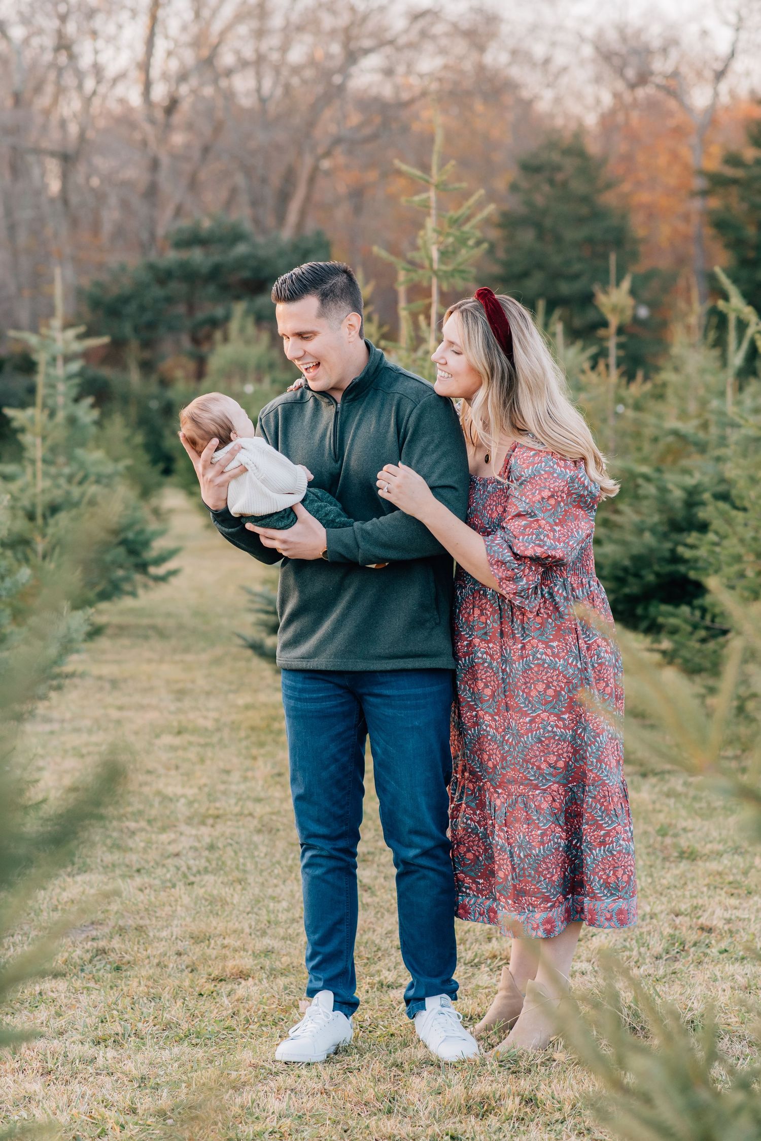 A father hold his son in his arms while his wife stands off to the side of him and smiles down at their son for a holiday mini session.