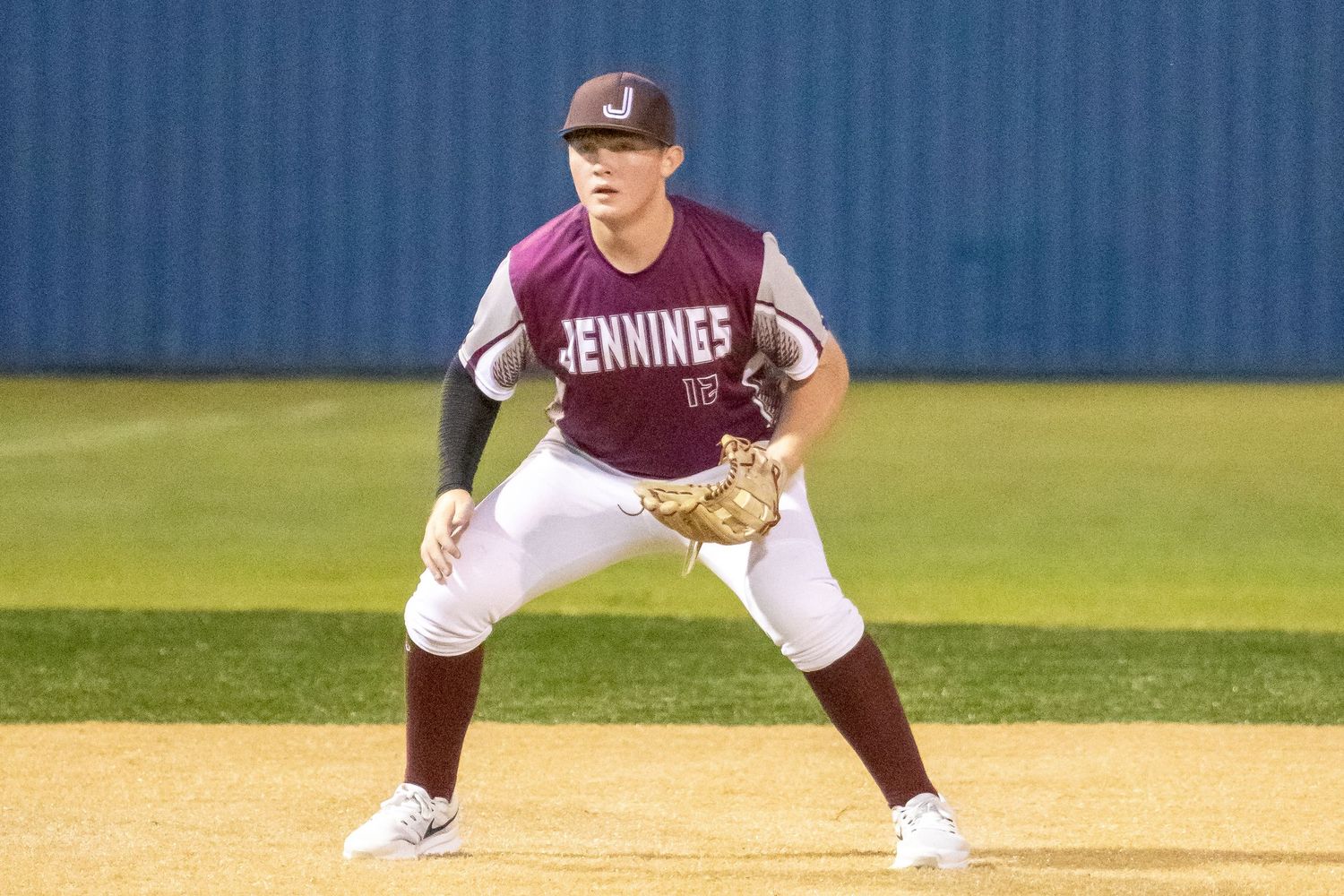 Baseball players in maroon uniforms positioned on baseball diamond during game.
