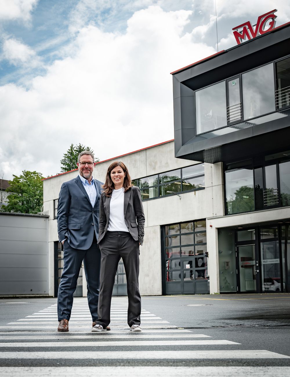 Geschäftsführer posieren vor dem Unternehmensgebäude, moderne Businessfotografie für Corporate Branding und Webpräsenz.