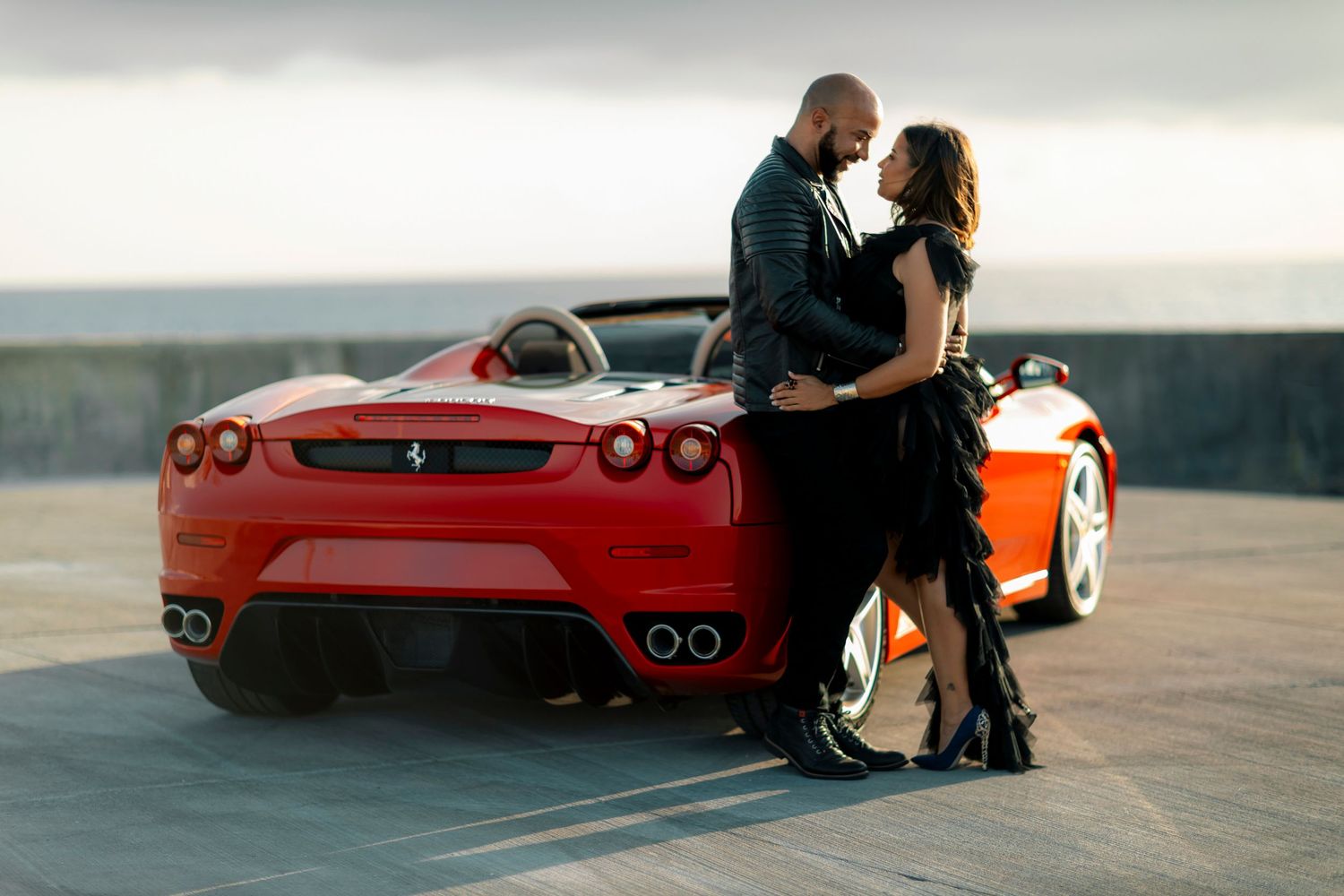 A romantic photoshoot with a red Ferrari sports car at sunset.