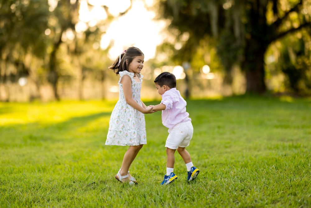 Family members playing and running together on grassy hill during sunset photoshoot. Photo by Dani De La Rosa, DigitalMyst Photography