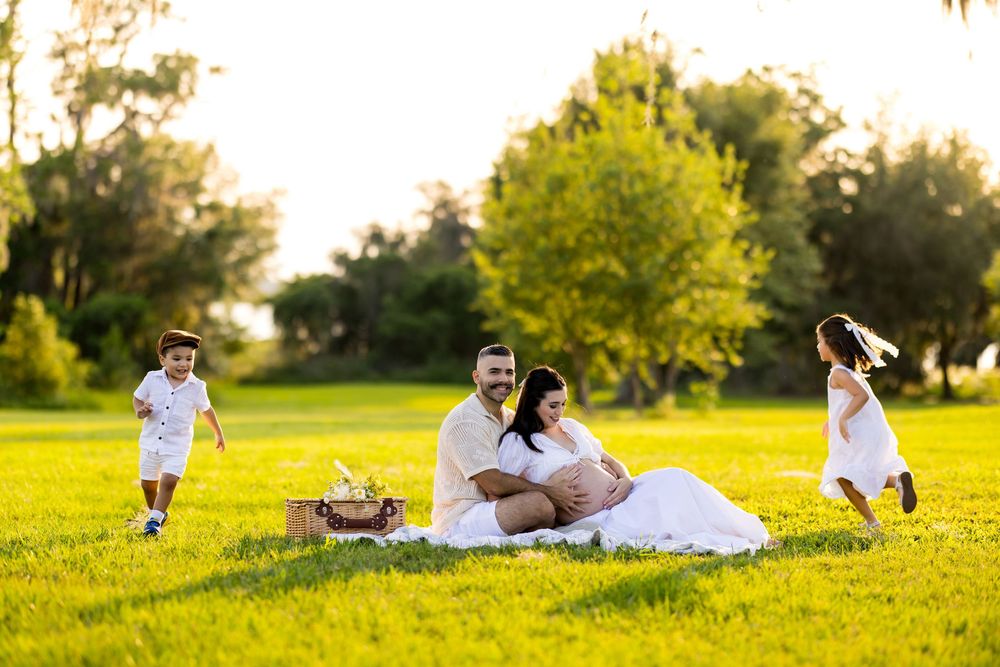 Golden hour family photoshoot with picnic setup in expansive grassy field. Photo by Dani De La Rosa, DigitalMyst Photography, Wesley Chapel