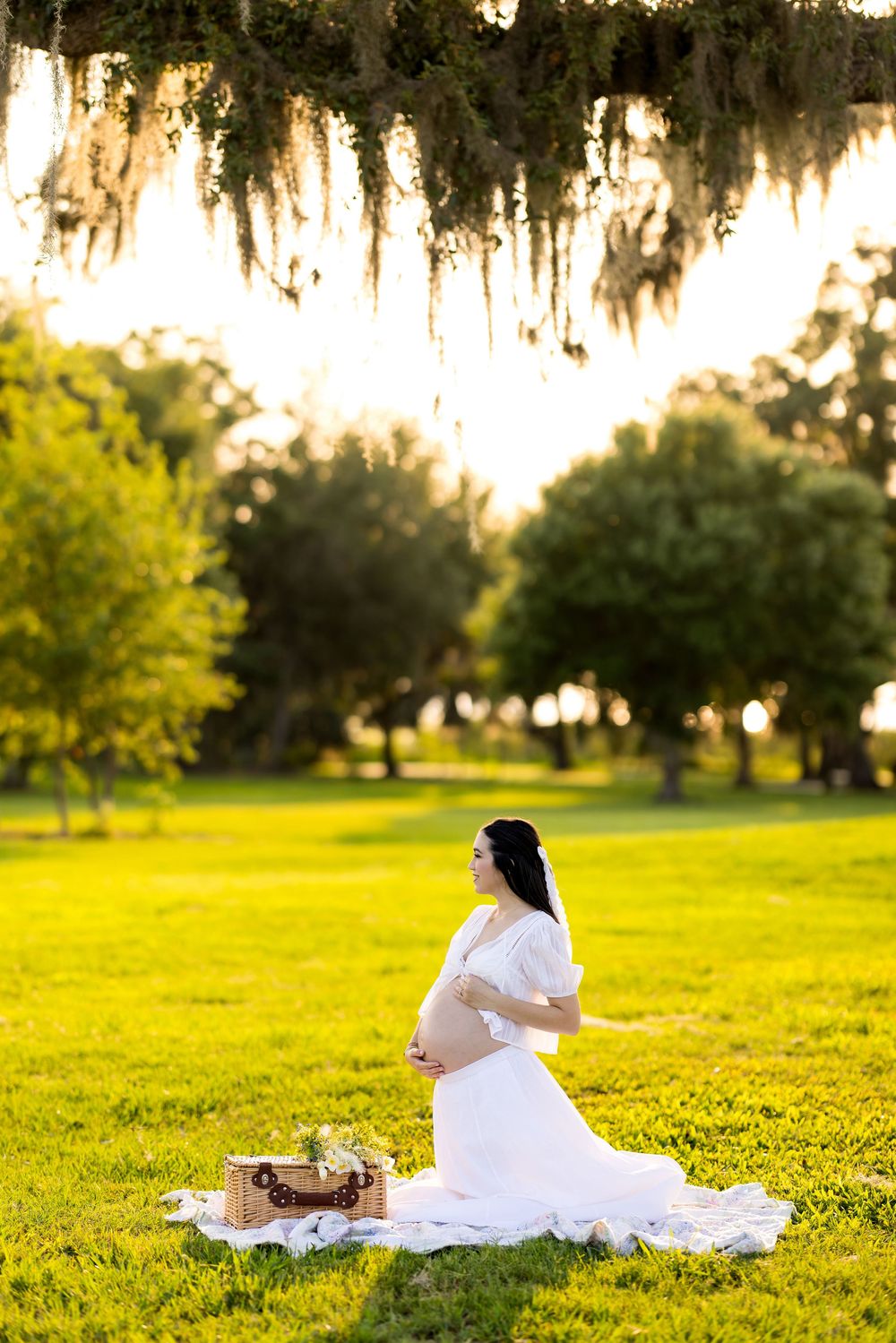 Maternity photography session in sunlit field with white dress and natural backdrop. Photo by Dani De La Rosa, DigitalMyst Photography, FL